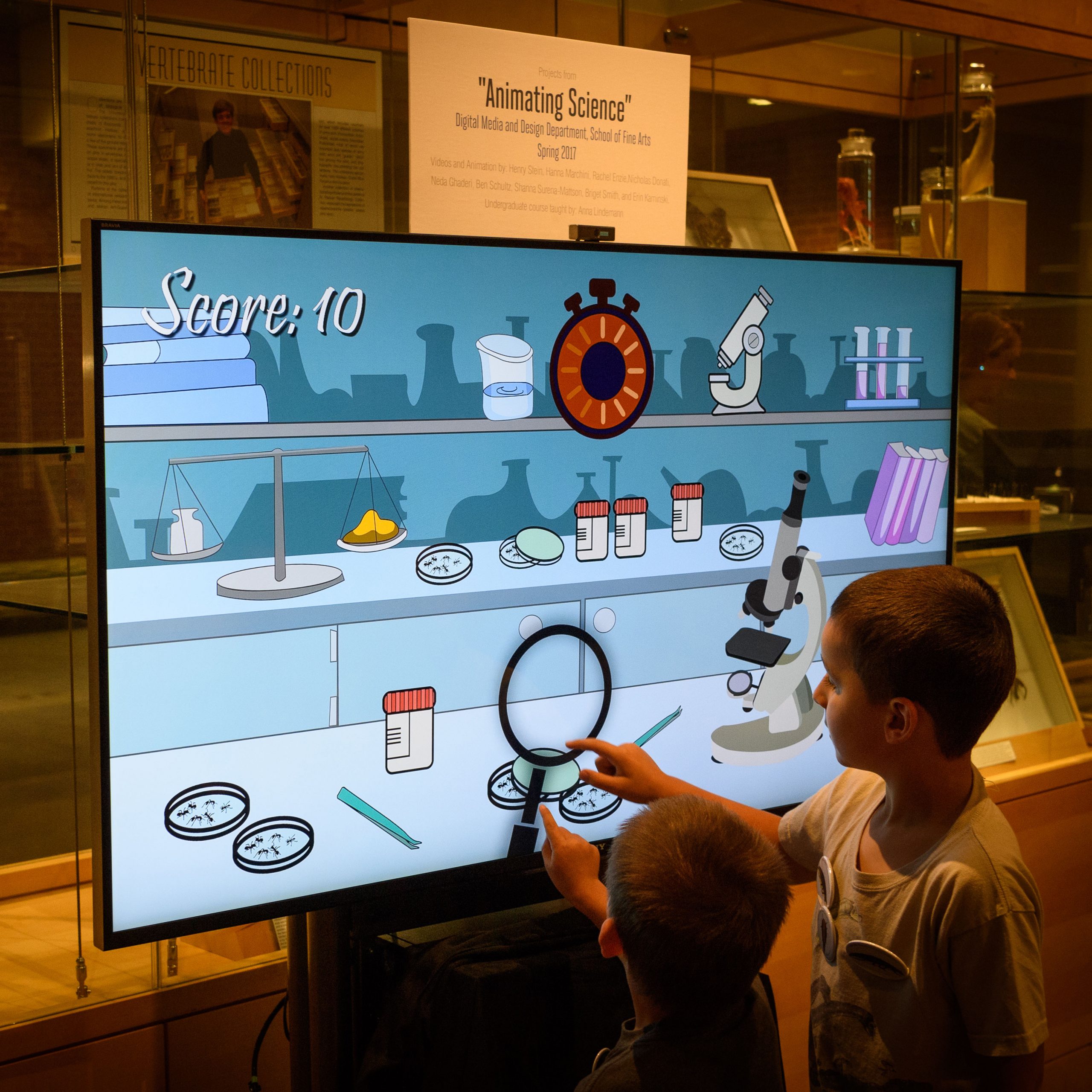 Brothers Knox, 4, and Lexin Mansell, 6, of Storrs, play a video game created by the Department of Digital Media and Design during UConn Extension Bug Week AntU Day at the Biology/Physics Building on July 27, 2017. (Peter Morenus/UConn Photo)